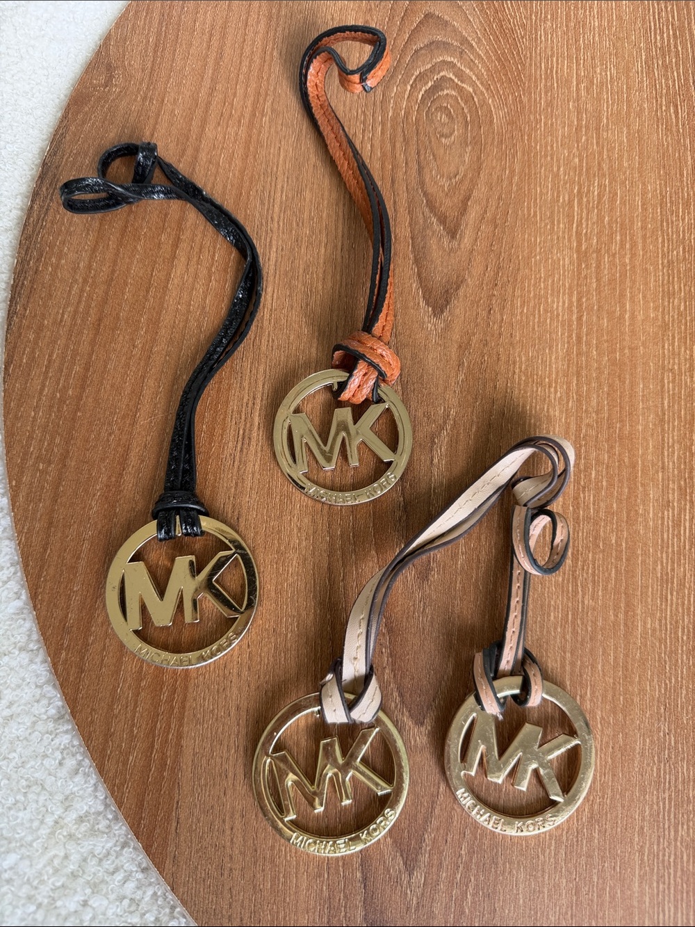 Set of four Michael Kors MK logo handbag charms featuring large round gold-tone